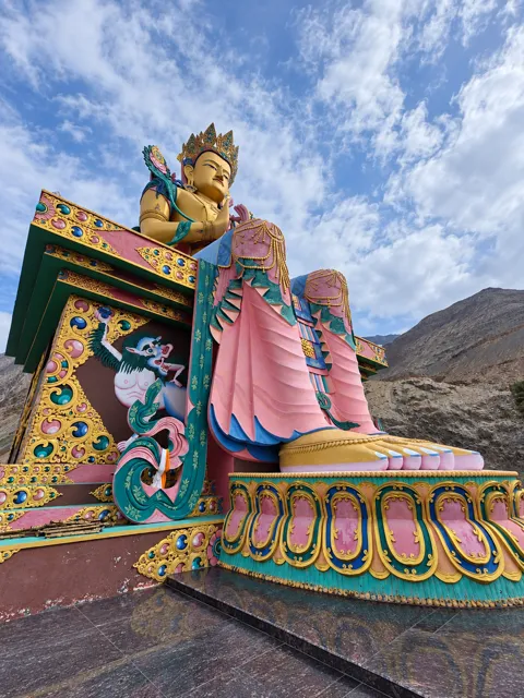Colourful Buddhist statue against mountain scenery